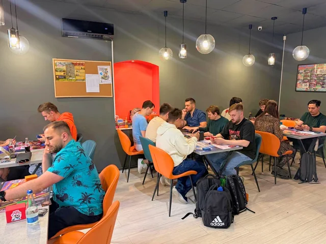 Partide de cărți la mesele cu scaune portocalii din KRIT Brașov