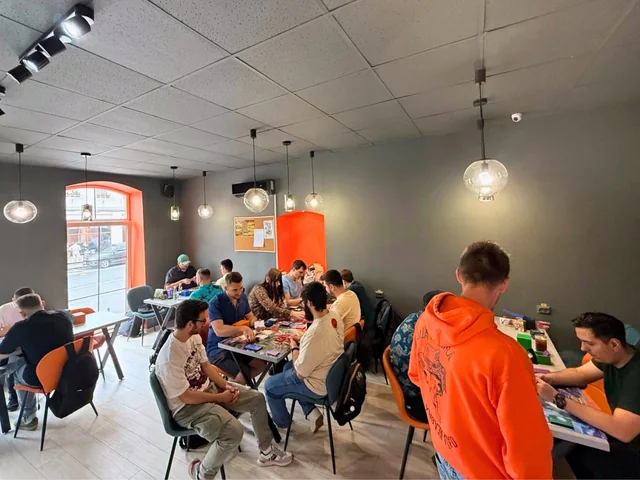 Sala de joc de la KRIT Brașov, cu jucători la mese lângă ferestre